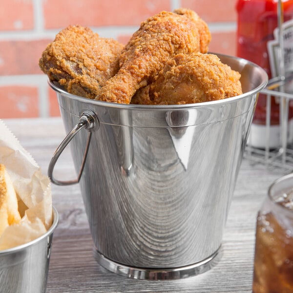 A Clipper Mill stainless steel serving pail filled with fried chicken on a table.