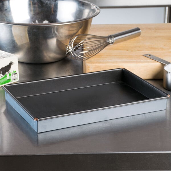 A Matfer Bourgeat rectangular non-stick cake pan on a counter with a bowl and whisk.