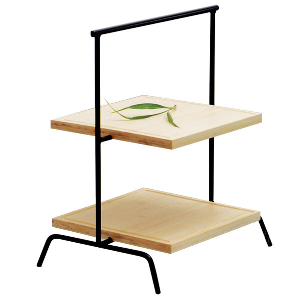 A Clipper Mill black iron 3-tier riser on a wood shelf with a green leaf on top.