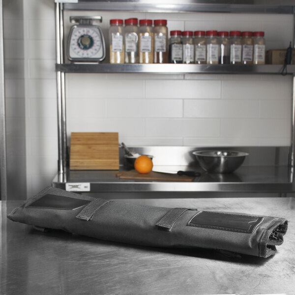 A black Dexter-Russell cutlery roll on a kitchen counter.