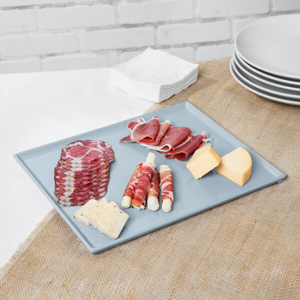 A gray Tablecraft rectangular cast aluminum platter with meat and cheese on a table.
