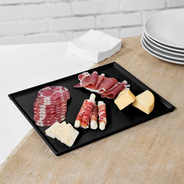 A Tablecraft black cast aluminum rectangular cooling platter with meat and cheese.