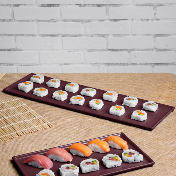 A Tablecraft maroon speckle cast aluminum long rectangular cooling platter with sushi and rolls on a table.