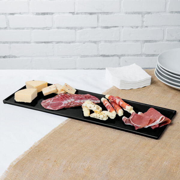A Tablecraft black cast aluminum rectangular cooling platter with green speckles holding a plate of meat and cheese.