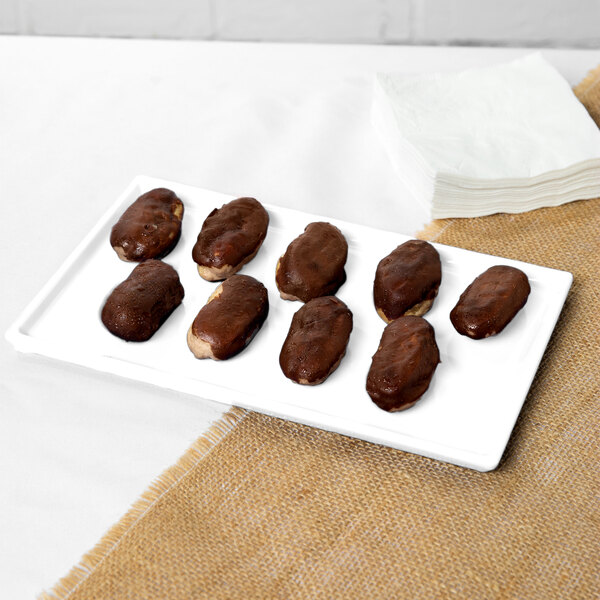 A Tablecraft white cast aluminum rectangular cooling platter holding chocolate covered dates.