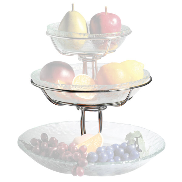 A Clipper Mill stainless steel three tiered fruit stand holding a bowl of fruit.