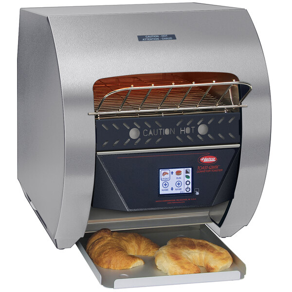 A Hatco stainless steel conveyor toaster with bread in it.