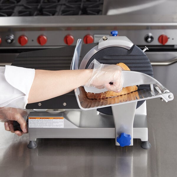 A person using a Vollrath medium duty meat slicer to slice meat.