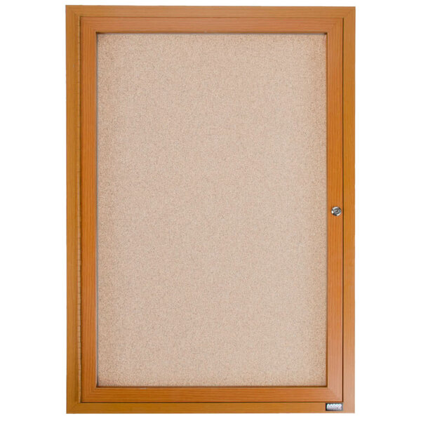 An enclosed wooden framed cork bulletin board with a key.