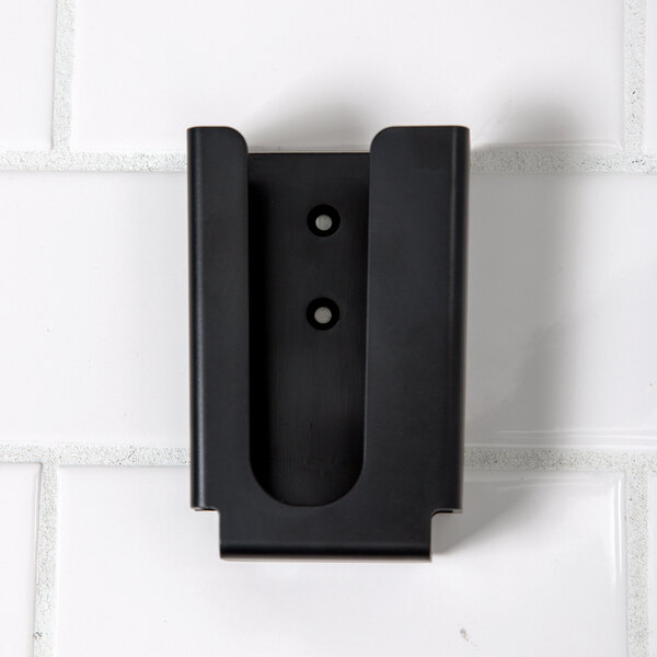 A black Cooper-Atkins AquaTuff wall-mount bracket on a white tile wall.