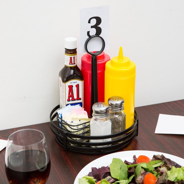A Choice wrought iron condiment caddy holding condiments and a salad on a table.