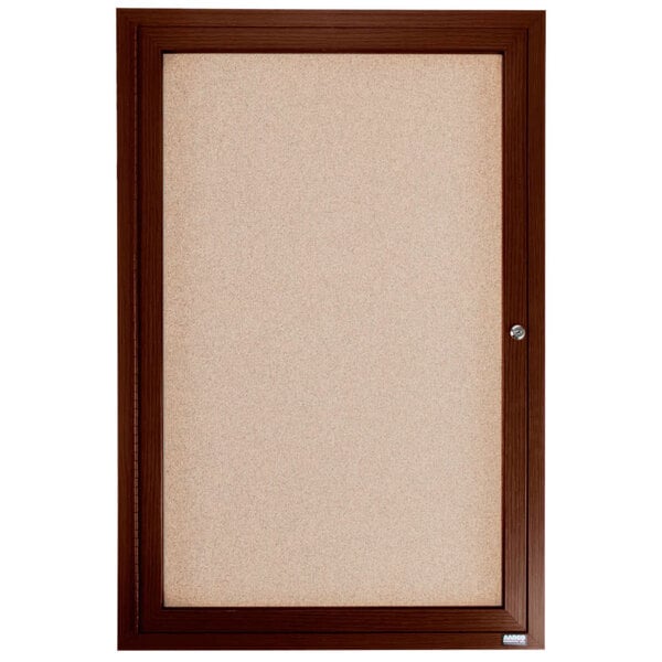 An enclosed walnut Aarco bulletin board with a silver knob.