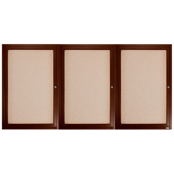 A group of Aarco walnut brown framed bulletin boards with white boards inside.