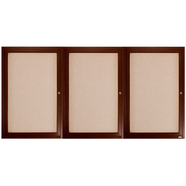 A brown framed Aarco bulletin board with three doors containing white boards.