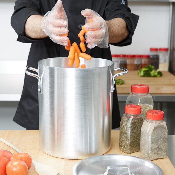 A chef putting carrots into a Vollrath aluminum stock pot.