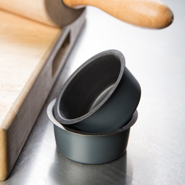 A stack of Matfer Bourgeat round ramekins with a rolling pin on a counter.