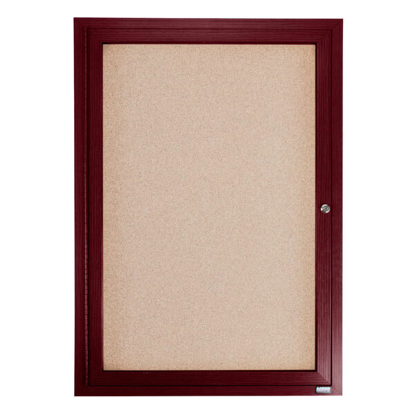 An Aarco cherry enclosed bulletin board with a cork background and a door.