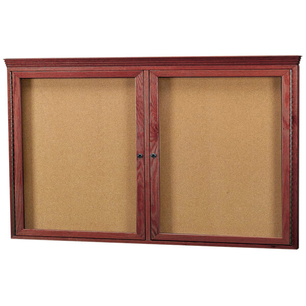 An Aarco enclosed cork bulletin board with a wooden cherry frame and crown molding.