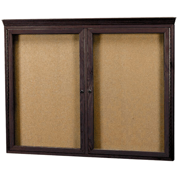 A wooden bulletin board with two hinged glass doors.