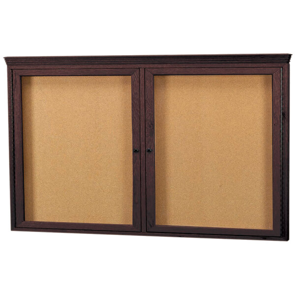 A brown wooden framed Aarco bulletin board with crown molding on a wall.