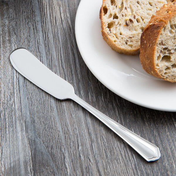 A Libbey stainless steel butter knife on a plate of bread.