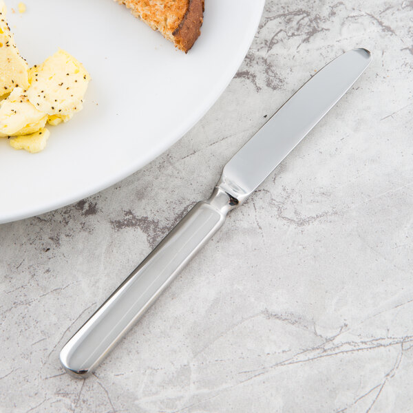 A Libbey stainless steel bread and butter knife on a plate of food.