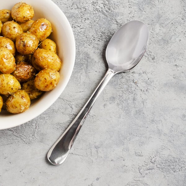 A bowl of roasted potatoes with a Libbey stainless steel serving spoon.