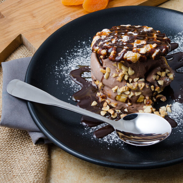 A plate of chocolate ice cream with nuts with a World Tableware stainless steel dessert spoon.