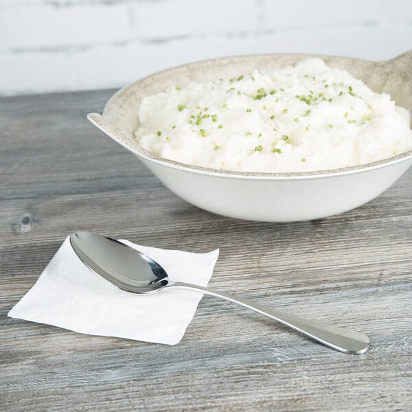 A bowl of mashed potatoes with a Libbey stainless steel serving spoon.