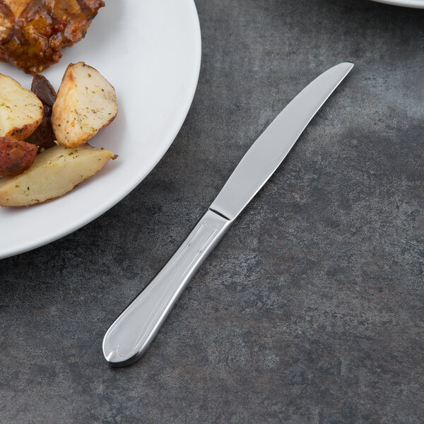 A plate of food with a Libbey Antique fluted solid handle steak knife on it.