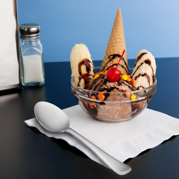 A bowl of ice cream with a Libbey stainless steel dessert spoon on a napkin.