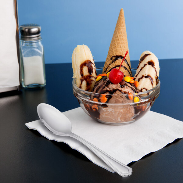 A bowl of ice cream with a Libbey Cortland dessert spoon, bananas, and chocolate toppings.