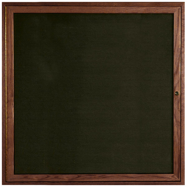 An Aarco enclosed black felt message board with walnut frame.