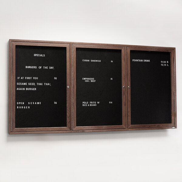 A black Aarco menu board with walnut frame and white text on it.