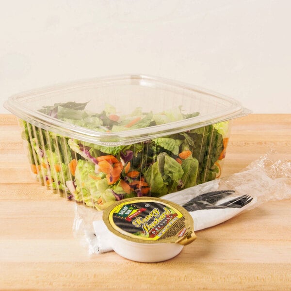 A clear Genpak plastic container filled with salad.