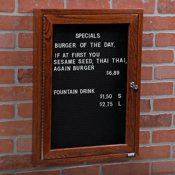 A black Aarco enclosed message board with a white sign on it with a picture of a burger.