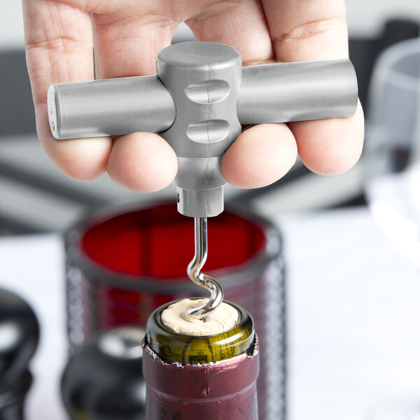 A hand holding a Franmara Silver Gray plastic pocket corkscrew and opening a bottle of wine.