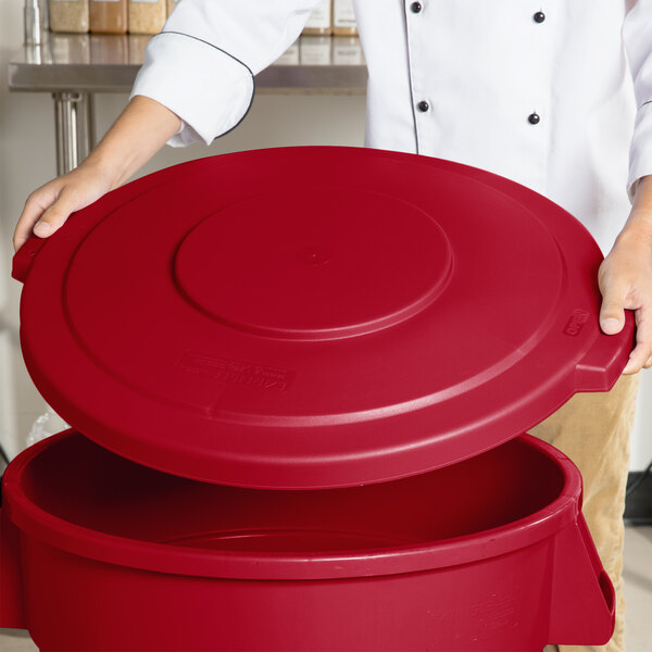 A person holding a red Carlisle Bronco trash can lid.