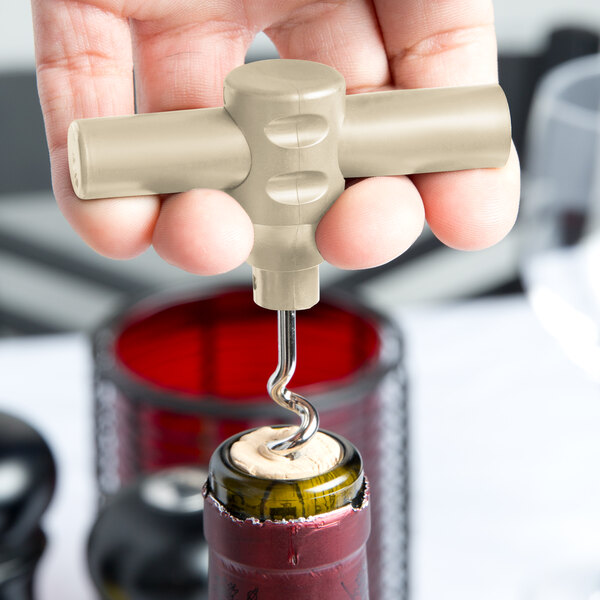 A hand using a Franmara plastic pocket corkscrew to open a wine bottle with a cork.