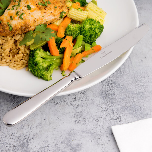 A plate of food with a Chef & Sommelier stainless steel dinner knife, broccoli, and carrots.