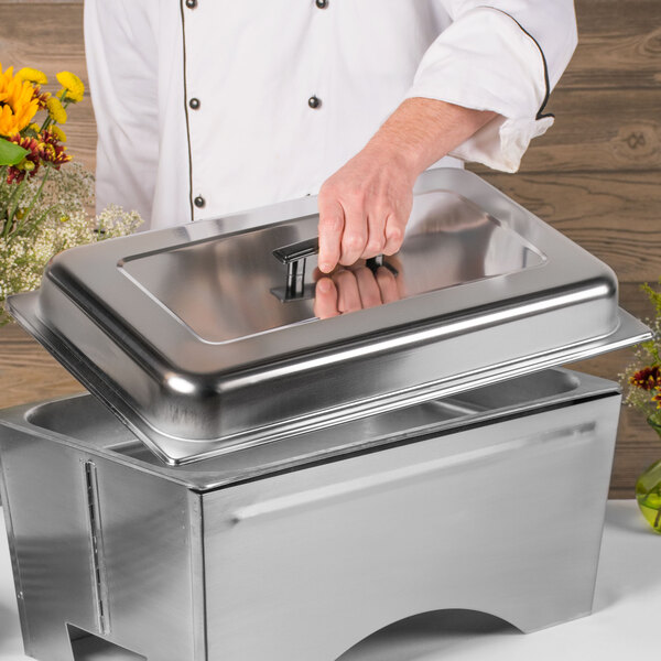 A person holding a Sterno stainless steel chafer cover over a metal container with flowers.