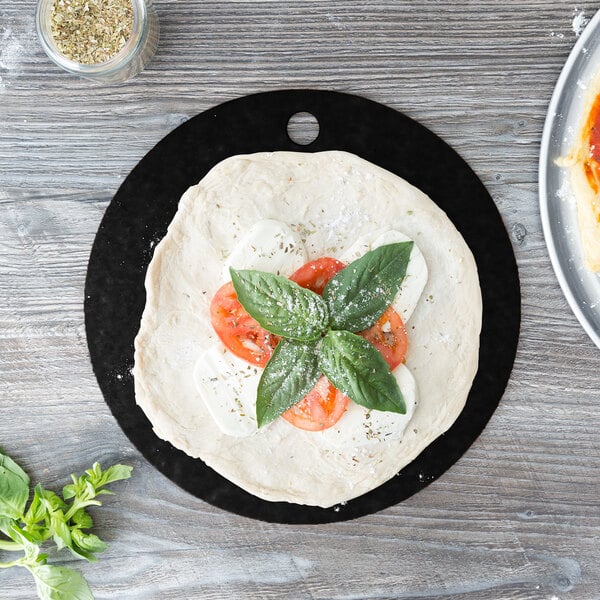 A pizza with tomatoes and basil on an Epicurean slate pizza board.