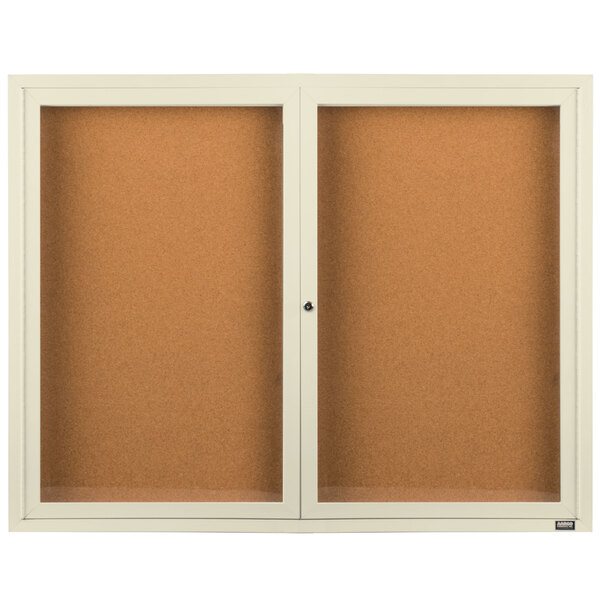 An Aarco ivory enclosed bulletin board cabinet with two glass doors.