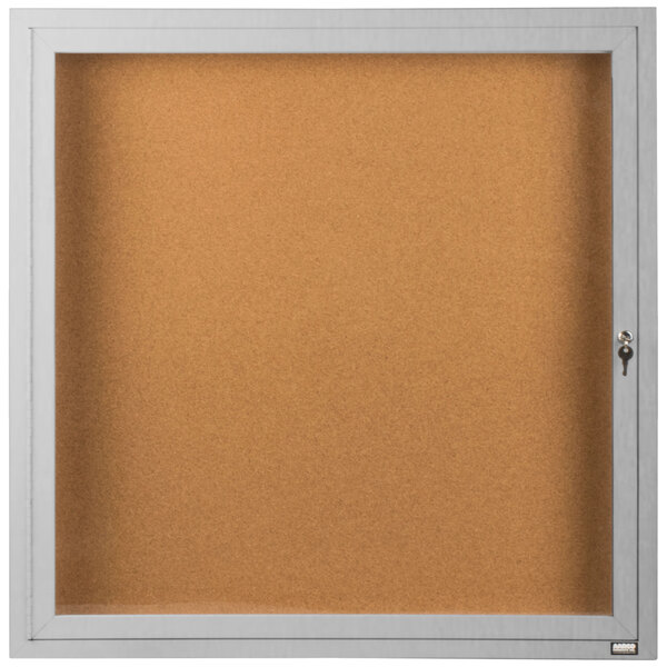 A white framed bulletin board with a glass door and key.
