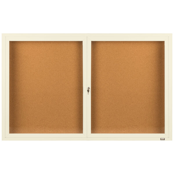 An Aarco ivory bulletin board cabinet with glass doors on a white background.
