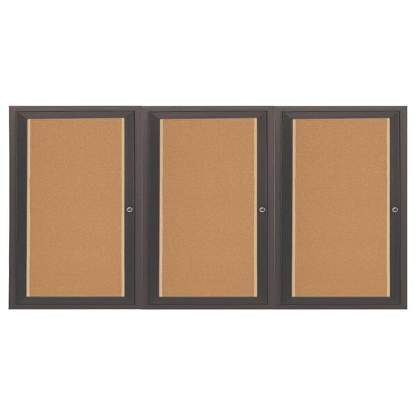 An Aarco bronze indoor bulletin board cabinet with 3 doors and cork boards inside.