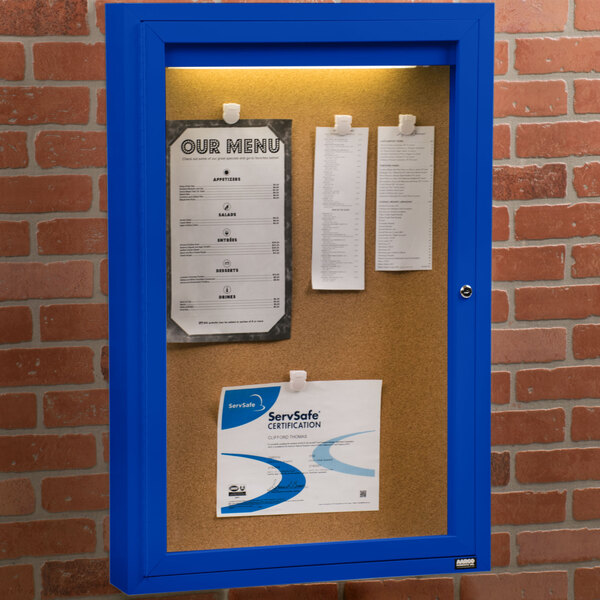 An Aarco blue indoor bulletin board cabinet with a sign on it.