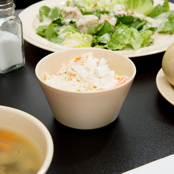 A Nustone Tan Melamine bouillon bowl filled with soup on a table.