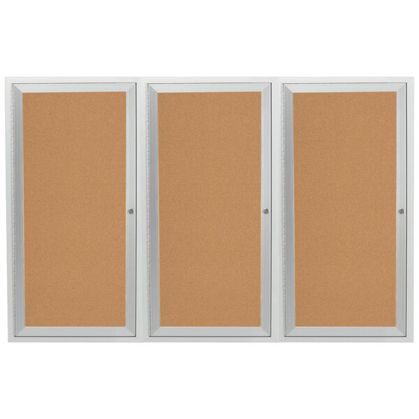An Aarco indoor bulletin board cabinet with three cork bulletin boards behind three doors.