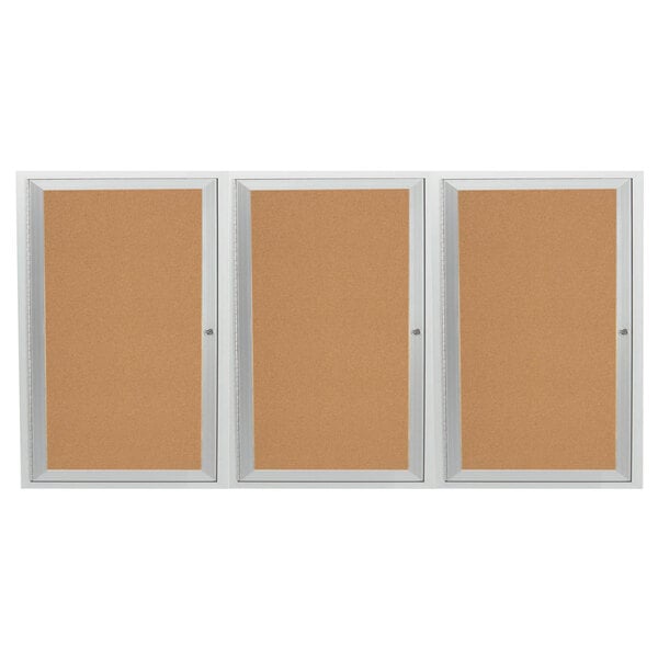 An Aarco satin anodized indoor bulletin board cabinet with three doors enclosing three cork boards.